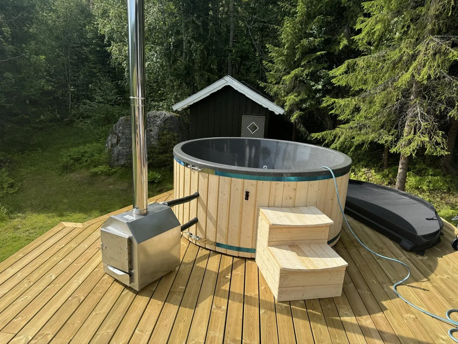 Utvendig vedovn i rustfritt stål koblet til en badestamp