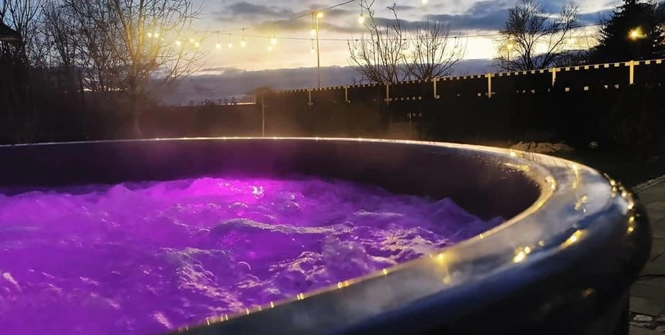 Badestamp med lilla lys i boblende vann i skumringen