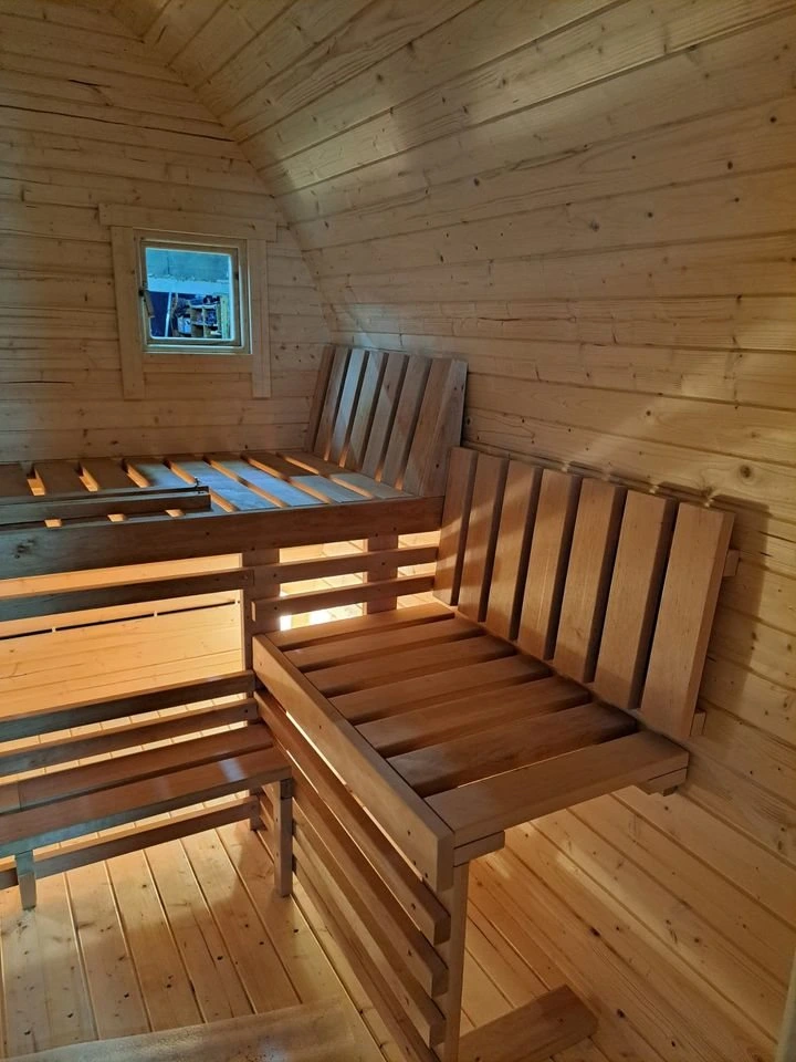 Innsiden av badstue med benker i to høyder og et lite vindu i gavlen