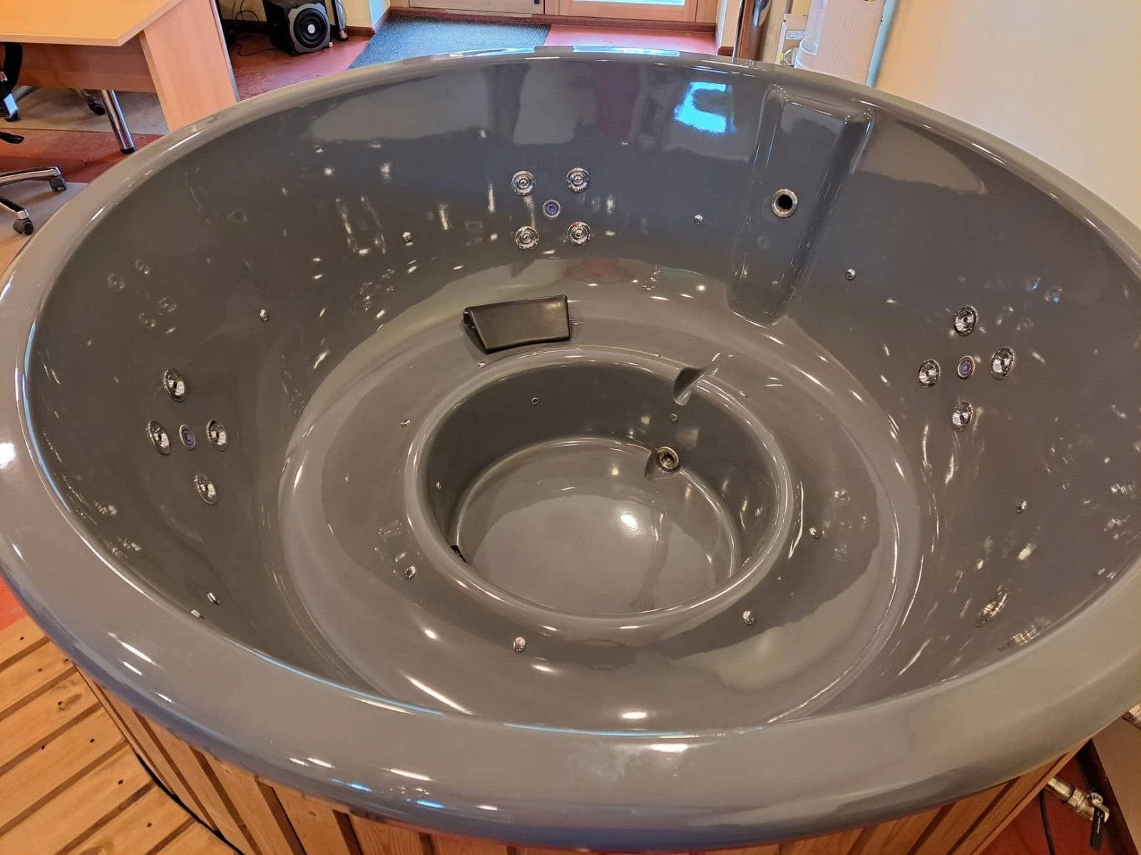 Mørkegrått badestampkar med nakkepute og dyser, i verkstedet