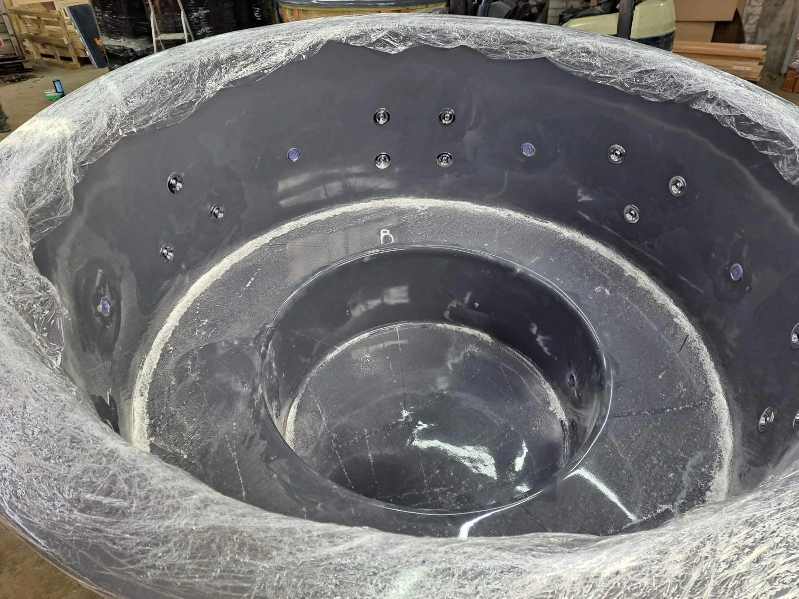 Mørkegrått badestampkar pakket inn i plast i verkstedet