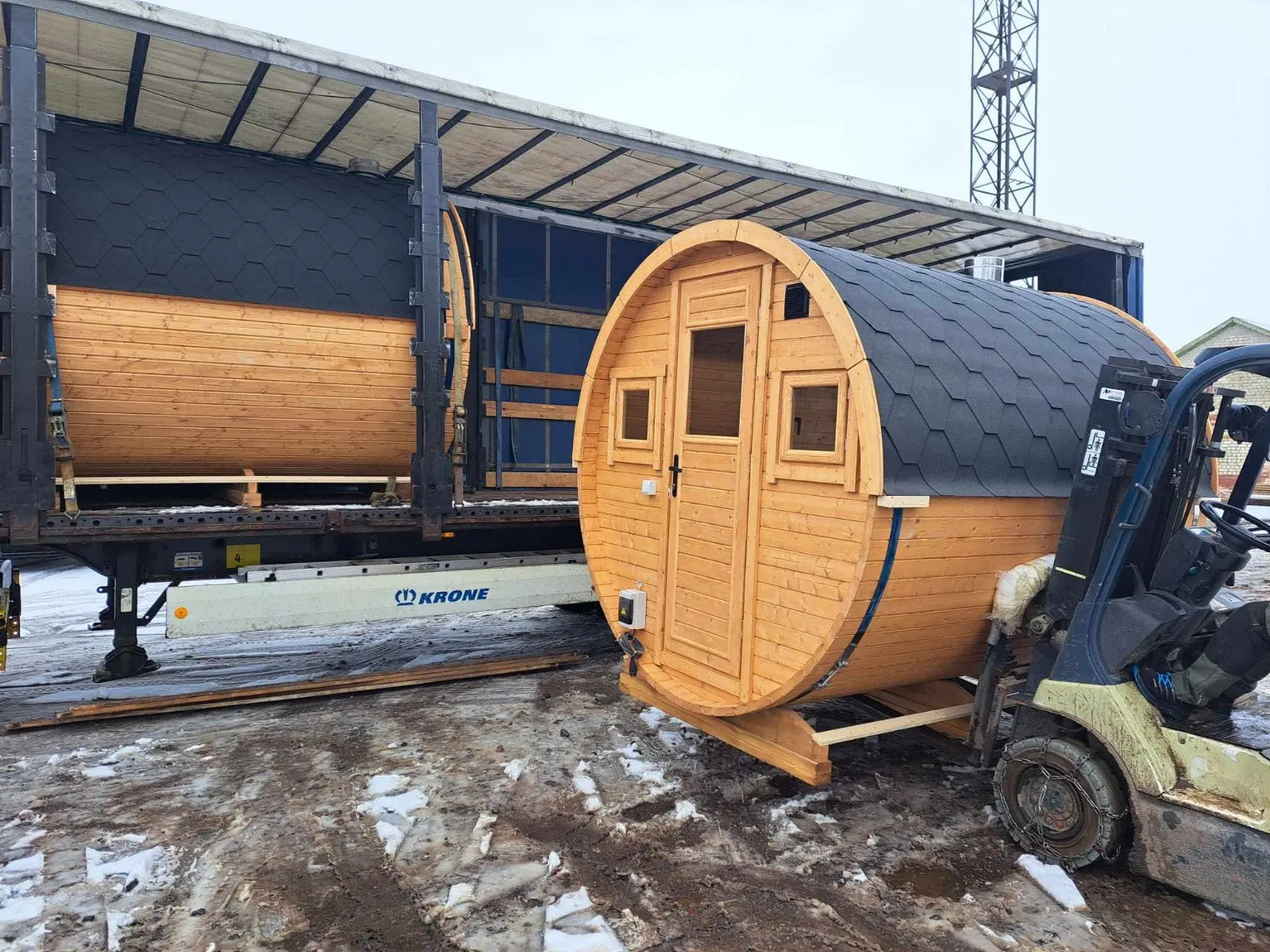 Tønnebadstue løftes med gaffeltruck ved en semitrailer
